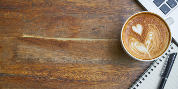 Das Foto zeigt eine Kaffeetasse und einen Laptop.