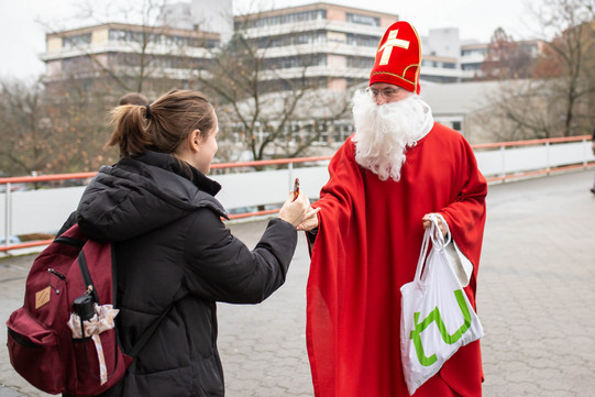 Das Bild zeigt Prof. Ballhorn als Nikolaus verkleidet beim Überreichen eines Schokonikolauses.